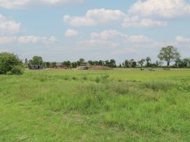 A grassy open field with playground equipment and picnic tables under a cloudy sky at The Heron in Lode near Bottisham