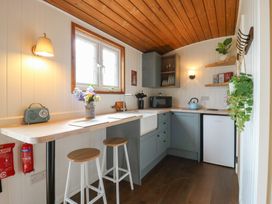 A kitchen with blue cabinets wooden ceiling stools and plants at Barn Owl in Lode near Bottisham