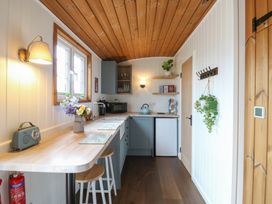 A kitchen with wooden ceiling and floor with stools and appliances at Barn Owl in Lode near Bottisham
