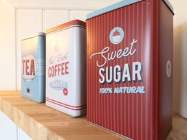 Three metal storage tins for tea coffee and sugar on a wooden shelf at Barn Owl in Lode near Bottisham