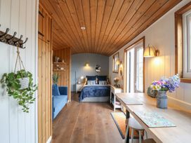 A bedroom with a bed blue sofa plants and a dining table at Barn Owl in Lode near Bottisham