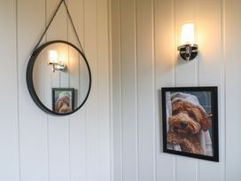 A wall with a round mirror hanging on a chain and a framed picture of a dog under a wall light at Barn Owl in Lode near Bottisham