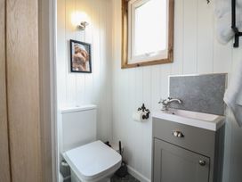 A small bathroom with a toilet sink window and a framed picture of a dog above the toilet at Barn Owl in Lode near Bottisham