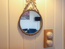 A round decorative wall mirror and two vintage rotary light switches on a wood panel on a paneled wall at Barn Owl in Lode near Bottisham