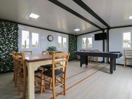 A room with a wooden table and chairs a pool table a wall clock and a television at Barn Owl in Lode near Bottisham