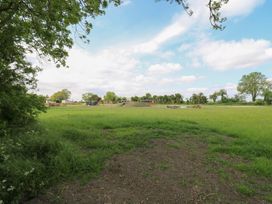 An open grassy field with picnic benches and a playground area under a blue sky at Barn Owl in Lode near Bottisham