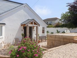 A house entrance with flowers and bench at Clova Brixham