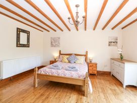A bedroom with a bed and side tables at Lakeside Barn Aylsham