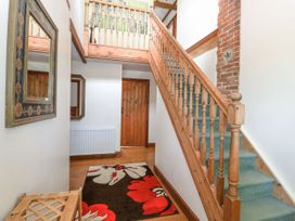 A hallway with stairs and a mirror at Lakeside Barn Aylsham