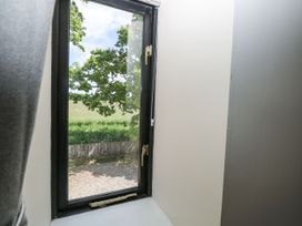 A window showing a view of trees and grass at Lakeside Barn Aylsham