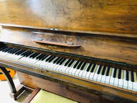 A piano with wooden finish and keys in a music room at Trenare in Truro