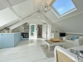 A living room with a kitchen area and a table at Trenare in Truro