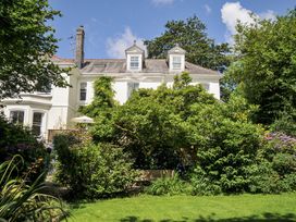 A garden with a house and greenery at Trenare in Truro