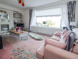 A living room with a pink sofa and floral carpet at 67 Pendre Avenue in Prestatyn