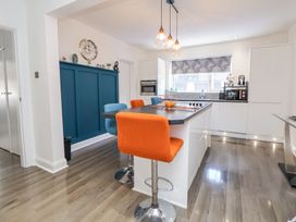 A kitchen with an island and orange and blue bar stools at 67 Pendre Avenue in Prestatyn