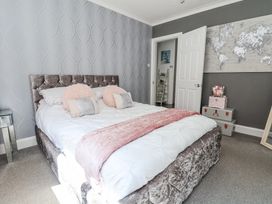 A bedroom with a bed with pink cushions and a pink throw a world map on the wall and stacked boxes at 67 Pendre Avenue in Prestatyn