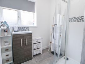 A bathroom with a shower enclosure, a sink cabinet, a small white storage unit, a towel rack ladder, and a frosted window at 67 Pendre Avenue in Prestatyn