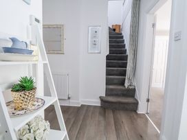 A hallway with wooden flooring a white shelf stairway with dark carpet and a doorway at 67 Pendre Avenue in Prestatyn