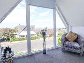 A seating area with a chair and a small table with binoculars by a large window showing a street and houses at 67 Pendre Avenue in Prestatyn