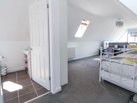 A bedroom with a white metal bed frame and a gray sofa in the background with a skylight window in the ceiling and an open door leading to a bathroom at 67 Pendre Avenue in Prestatyn