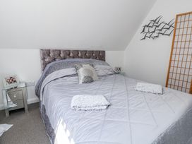 A bedroom with a bed covered in gray bedding two towels on the bed mirrored bedside tables family photos and wall art at 67 Pendre Avenue in Prestatyn