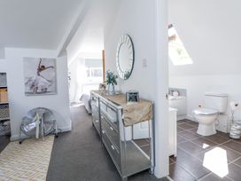 A hallway with a mirrored dresser and a round mirror next to a bathroom with a toilet and a bathtub at 67 Pendre Avenue in Prestatyn