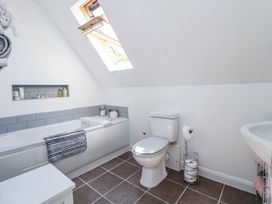 A bathroom with a bathtub a toilet a skylight window and tiled floor at 67 Pendre Avenue in Prestatyn