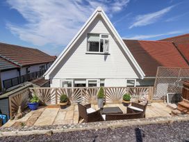 An outdoor patio area with a wooden fence table chairs potted plants and statues in front of a white house with a triangular roof at 67 Pendre Avenue in Prestatyn