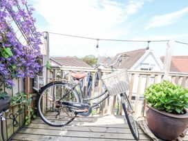 A wooden balcony with a bicycle and potted plant with purple flowers at 67 Pendre Avenue in Prestatyn