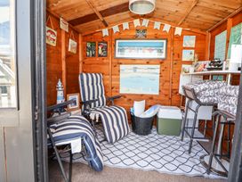 A wooden shed interior with striped reclining chairs a rug bar stools wall art and various decorations at 67 Pendre Avenue in Prestatyn