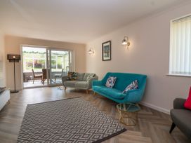 A living room with two sofas a glass door leading to a dining area and a patterned rug at Hillside in Bishops Cleeve