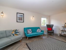 A living room with two sofas a patterned rug a window and wall lights at Hillside in Bishops Cleeve