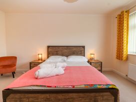 A bedroom with a wooden bed frame and headboard with white pillows and a pink blanket at Hillside in Bishops Cleeve