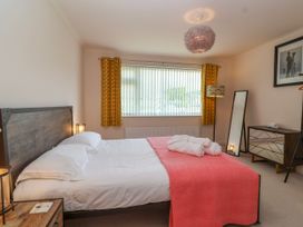 A bedroom with a bed with white sheets and a coral blanket at Hillside in Bishops Cleeve