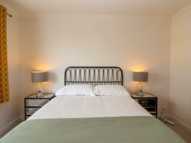 A bedroom with a double bed two bedside tables with lamps and yellow patterned curtains at Hillside in Bishops Cleeve