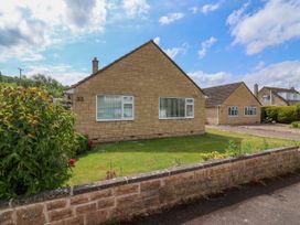 A stone bungalow with two windows and a garden surrounded by a low stone wall at Hillside in Bishops Cleeve