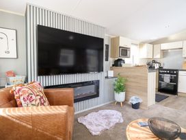 A living room with a television and kitchen area at Number 34 Foxburrow Hang in Great Yarmouth
