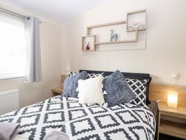 A bedroom with a bed and decorative shelf at Number 34 Foxburrow Hang Great Yarmouth
