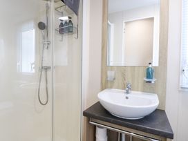 A bathroom with a shower, sink, and mirror at Number 34 Foxburrow Hang in Great Yarmouth