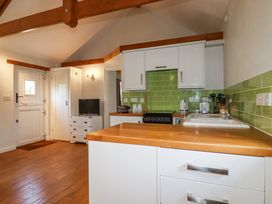 A kitchen with wooden countertops white cabinets green tiled backsplash and a small television at Rose's Stable Bodrean near Truro