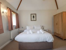 A bedroom with a bed with white linens and towels two bedside tables with lamps a wardrobe and curtains at Rose's Stable in Bodrean near Truro