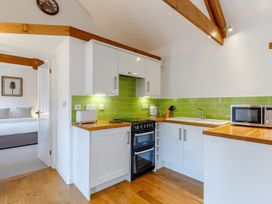 A kitchen with white cabinets wooden countertops green tile backsplash and a doorway to a bedroom at Roses Stable Bodrean near Truro