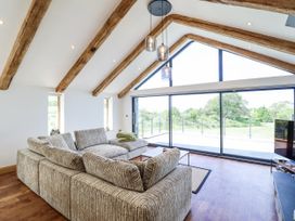 A living room with a sofa facing a large window at Perth Y Deri in Llanddwywe