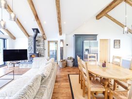 A living room with a sofa and dining area at Perth Y Deri in Llanddwywe