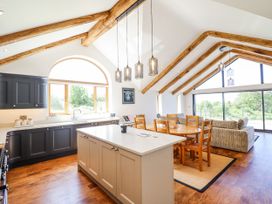 A kitchen with dining area and large windows at Perth Y Deri in Llanddwywe