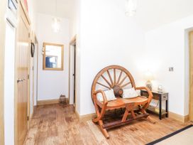 A hallway with a wooden chair and a mirror at Perth Y Deri in Llanddwywe