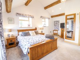 A bedroom with a wooden bed and nightstand at Perth Y Deri in Llanddwywe