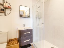 A bathroom featuring a shower and a sink with a mirror at Perth Y Deri in Llanddwywe
