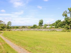 A grassy field with a path and stone wall at Perth Y Deri in Llanddwywe