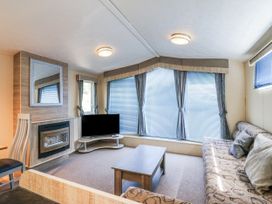 A living room with a sofa and television at White Hart Caravan in Battle